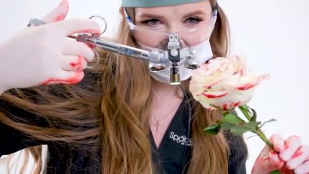 大規模な注射器を持つ女性医師が麻酔のレッスンでバラの花のアレゴリーへの注射を行います操作がどのように行われ 手袋の血中眼鏡やマスク医療スーツにバラ — ストック動画