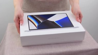 Kadın elleri, Apple 'dan gelen MacBook 14 Pro' nun beyaz kutusunu M1 ev hanımı önlük mutfak önlüğü hediye paketi Ukrayna Vinnitsa 2023 'ten alınması gereken bir eşya ile açıyor.