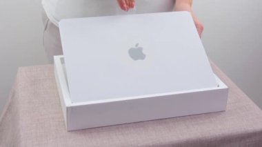 woman takes out new macbook from a white box buying latest technology joy close-up female hands sign apple special packaging just from store gift seller demonstration unpacking Ukraine 2023