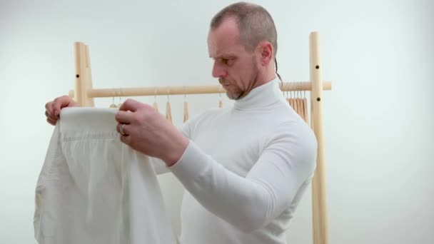 Man Background Wooden Hanger White Clothes Grimaces Trying Putting Shirt — Stockvideo