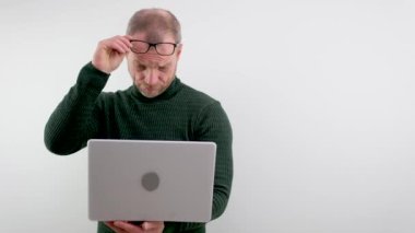 adult man lifted glasses to marshal looking at laptop he does not believe eyes interest inquisitiveness buying selling online white background space for text advertising bad eyesight ophthalmologist