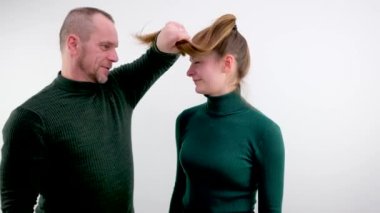 Erkeklerin kızların saçlarını sarmaladığı komik bir fotoğraf. Aile baskısı altındaki baba-baba ilişkilerinde çocukların ve yetişkinlerin kötü davranışlarıyla yüzleşiyorlar. Güzellik için beyaz arka plan tasarımında fedakarlık gerekiyor.