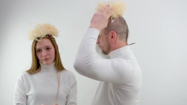 man and girl on white background pretend to be angels in their hands a box of packing materials on peoples heads. interesting delivery Angel delivery unpacking. funny people head nest