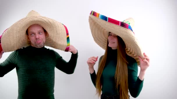 大人の男と若い女の子ホールドオン彼らの頭Sombrero帽子スペイン語Headdress喜びで購入時にダークグリーンゴルフで歩くHeaddress販売服楽しい旅メキシコの休日Buenos Muchachos — ストック動画