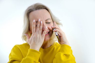 Beklenmedik bir haber sunan kadın, utangaç, utangaç, orta yaşlı, parlak duyguları olan, yüzünde gülümseme ile telefonda konuşur.