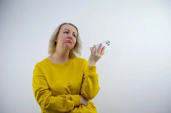 Niezadowolona Smutna Kobieta Rękach Telefonem Wypchanym Ustami Stoi Zdenerwowana Białym — Zdjęcie stockowe