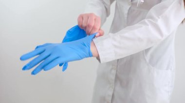 İki mavi tıbbi eldiven, beyaz bir arka planda yalıtılmış ve elleri var. Lastik eldiven üretirken, insan eli lateks eldiven takıyor. Doktor ya da hemşire azot koruyucu eldiven takıyor.