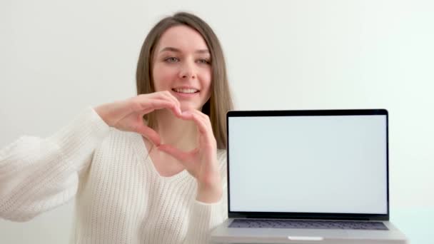 Ragazza Mostra Cuore Con Mani Uno Sfondo Bianco Vicino Computer — Video Stock