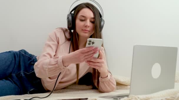 Dívka Leží Podlaze Pracuje Smartphone Doma Vedle Notebooku Sluchátka Odpočinek — Stock video