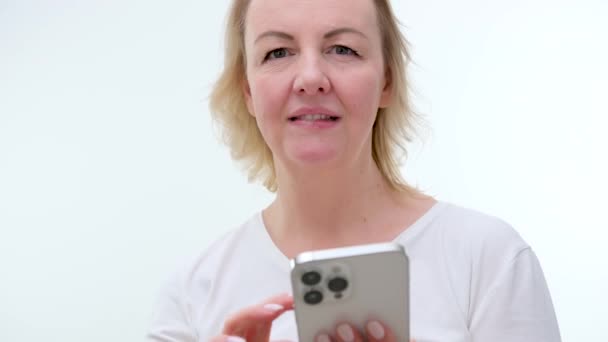 Close Vrouw Bladert Door Pagina Witte Telefoon Zachte Glimlach Middelbare — Stockvideo