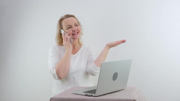 Mulher Falando Por Telefone Apontando Com Mão Para Mesa Laptop — Vídeo de Stock