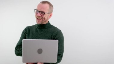 middle-aged man balding in glasses holding laptop joyful fun he shows his feelings to others he is a professor in a dark green golf radiates vibes of joy to students a lecture for lectures with laptop