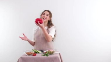 Ağır çekim HD 240 fps genç kız kırmızı dolma biber fırlatıyor. İçtenlikle gülüyor. Yemek pişirme programı için yer ve mekan.