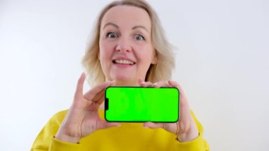 Elinde yeşil krom anahtarı olan yatay telefon ekranı tutan telefon reklamcısı kadın yüz eğlencesine parmağını gösteriyor.