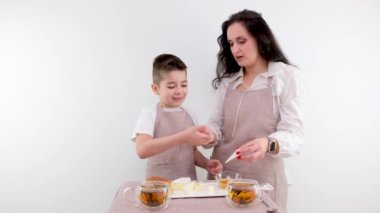 Kahvaltı anne ve oğlu peyniri deneyin çocuk peynir siyah çayın üzerine bal koyuyor masaya kahkaha eğlenceli eğlence aile gülümsemesi mutfak önlüğü beyaz peynir tabağı