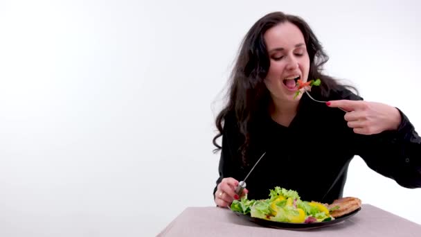 女は肉片をじっくり噛む美しいライトヘア黒髪の中年女性の顔ステーキサラダを食べる — ストック動画