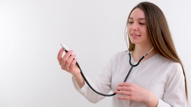 医学专业的女大学生学会了正确使用留声机 她的手拿着检测仪 检查着穿着白衣的笑容 对未来的医生进行白种人背景的训练 — 图库视频影像