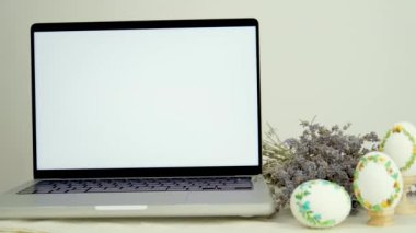 Pankart reklamında lavanta desenli üç yumurta işlemeli beyaz dizüstü bilgisayar ekranı. Paskalya bayramında ailenle mesajlaştığın için tebrik ederim.