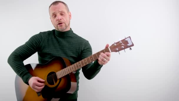 Muziekmelodie Onder Coupletten Volwassen Zelfverzekerde Man Speelt Gitaar Witte Achtergrond — Stockvideo