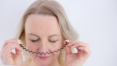 Siyah halka kullanan bir kadın saçını temizliyor makyaj için hazırlanıyor banyoda beyaz bir arka planda temizlik yapıyor aynada kendine dikkat ediyor maske takıyor