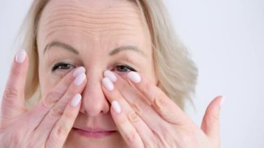 Masaj yapan kadın parmaklarıyla nazikçe gözlerine masaj yapar makyaj yapan kadın rimel akışını düzeltir tatilden sonra gözlerindeki yorgunluğu giderir.