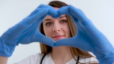 Kırmızı arka planda kalp şeklinde bir jest yapan kadın ellerinin yakın çekimi. Sevgililer Günü konsepti. Aşk duygularını ifade eden romantik bir jest. Yüksek kalite 4k görüntü