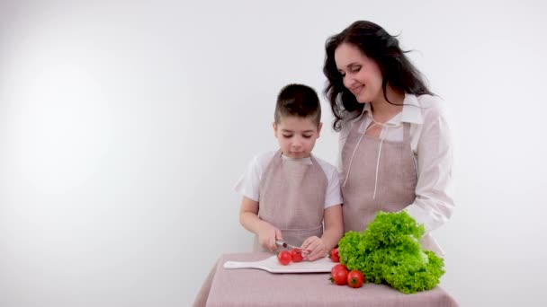 ママと息子は台所で料理を一緒に作る 大人の男の子はお母さんが野菜サラダを作るのを助ける 少年はオリーブオイルを緑の野菜に注ぐ 健康的なライフスタイルのコンセプト 高品質の写真 — ストック動画