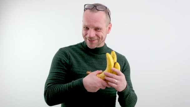 男人手里拿着香蕉显示出他们的数量笑着打开他额头上的眼镜喜剧视频蔬菜水果好的食物三个香蕉 — 图库视频影像