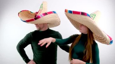 Meksika şapkalı kadın ve erkek. Yeşil kazaklı beyaz arka plan. Yan seyahat eğlencesine yaslanmış seyahat acentesini bekliyor.