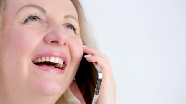 明るい誠実な笑いブロンド中年女性クローズアップ顔で電話で話して終わりに彼女の唇を追求しない彼女は会話の終わりが好きではない — ストック動画