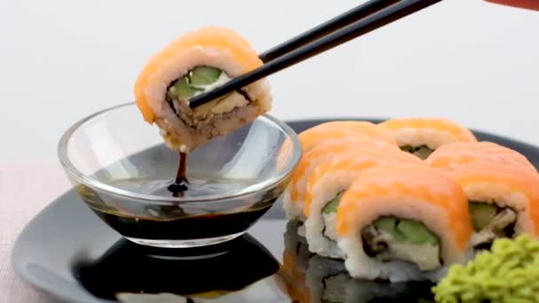 白皿に盛り付けられたサーモン寿司 寿司は サーモン 赤キャビアでロールします 新鮮なサーモン 柔らかいアボカド エビとカニ クリームチーズを幅広い層のマサゴキャビアの下で転がす — ストック動画