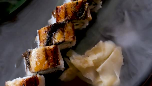 얼음으로 돌판에 참치와 뱀장어를 초밥을 곁들여 식탁에 맛있는 요리는 야자수 — 비디오