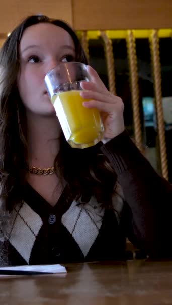 Ένα Κορίτσι Πίνει Χυμό Πορτοκαλιού Ανανά Σκοτεινό Εστιατόριο Ένας Έφηβος — Αρχείο Βίντεο