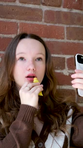 若い女性が口紅で唇を塗ります メイクを行う美しいブルネットのモデル 女性はカメラの前で化粧をする 化粧品の概念 4Kスローモーション映像 クローズアップビュー 高品質フルHd — ストック動画