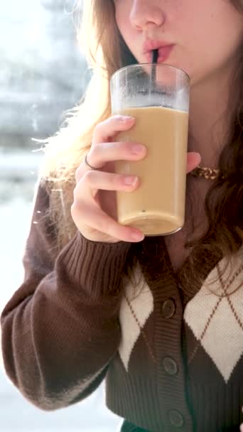 10代の女の子のクローズアップ唇ガラスカップ茶色のジャケットでミルクとカプチーノ冷たいコーヒーを飲む首飾りおいしいコーヒーショップの周りロフトスタイルチェーン楽しい時間 — ストック動画