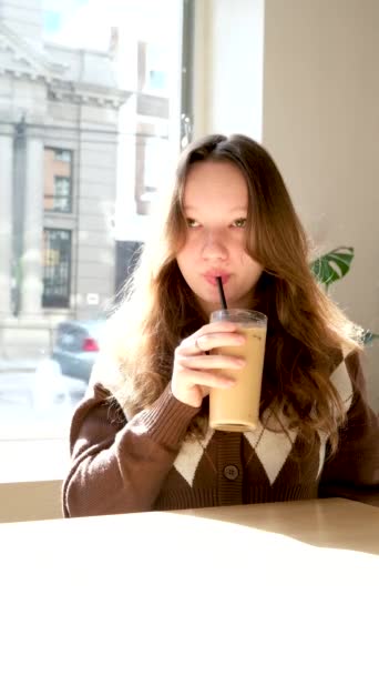 少女的亲密唇 喝着卡布奇诺冰镇咖啡 牛奶在杯子里 棕色夹克阁楼风格的链子环绕着脖子装饰美味的咖啡店 享受时光 — 图库视频影像