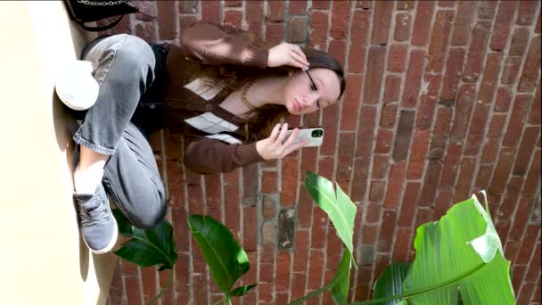 Tuğla Duvarın Arka Planındaki Güzel Genç Kız Kirpiklerini Boyuyor Telefon — Stok video