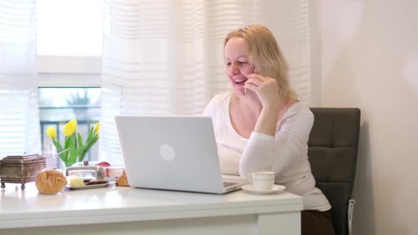 Kobieta Jedząca Śniadanie Przy Stole Pracująca Laptopie Rozmawiająca Przez Telefon — Wideo stockowe