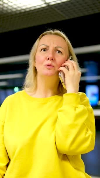 Γυναίκα Μια Φωτεινή Κίτρινη Φόρμα Μιλάει Θυμωμένα Στο Τηλέφωνο Ρωτά — Αρχείο Βίντεο