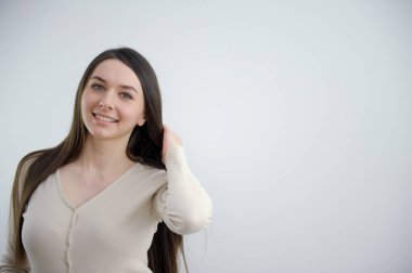 Güzel bir kız çerçeveye bakar, gülümser, sevinç, samimi gözler, güzel görünüm, beyaz uzay yazıtları için stokçu kadın.