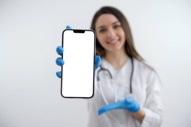 Beyaz ekranlı doktor, beyaz arka plan için mavi eldivenli bir el gösteriyor. Reklamınız arka plan cihazında bulanık bir şekilde gülümseyen güzel bir kadın.