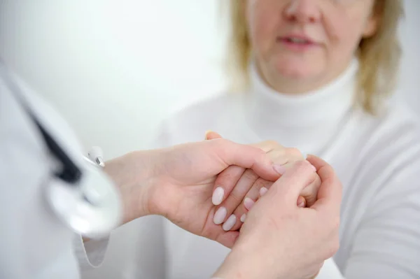 doctor holding the hand of the patient middle-aged woman adult in white clothes advertising help communication treatment caring on a white background doctor nurse