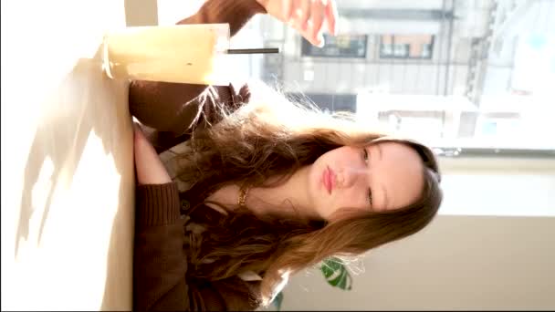 公園の階段に座ってアイスコーヒーを飲む幸せな美しい女の子 — ストック動画