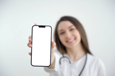 Güzel bir bayan doktor beyaz arka planda izole edilmiş akıllı bir telefon ekranı gösteriyor. Yüksek kalite fotoğraf