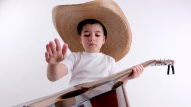 Kanepede oturan 5 yaşındaki beyaz çocuk akustik gitar çalıyor. Çocuk evdeyken gitar çalmayı öğreniyor. Evde gitarla vakit geçirmek, çocukların müzik tutkusu. Yüksek kalite