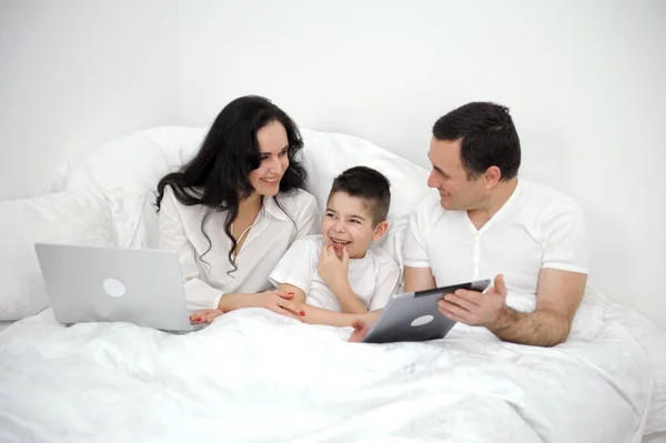 Family sitting on the sofa looking at laptop, studio shot. family and son watching and play tablet on bed High quality photo