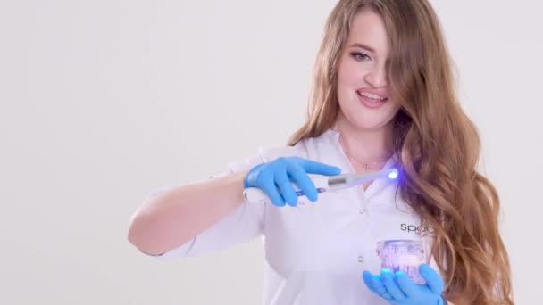 Piękny Lekarz Pływającymi Włosami Niebieskich Rękawiczkach Demonstruje Fotopolimerową Lampę Pacjentka — Wideo stockowe
