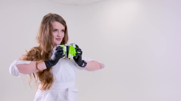 Blt Straumann 一位戴乳胶黑手套的漂亮女医生 在乌克兰2023年的白色工作室背景下 手持6箱假牙植入物 用于假牙治疗 — 图库视频影像