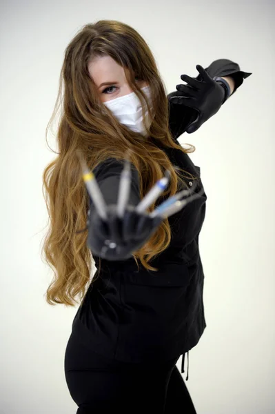 a woman dentist dances like a ninja in her hands she has a scaler and a curette she is wearing a mask in black gloves dark clothes loose hair gorgeous girl dentist doctor doctor on a white background