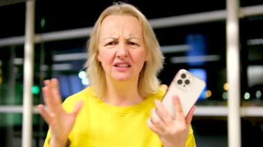 Ofiste küfür eden kızgın bir kadın telefon çağrısına şaşırdı. Hoş olmayan bir mesaj. Alnı buruşmuş, sarı takım elbiseli, sarışın bir kadın.